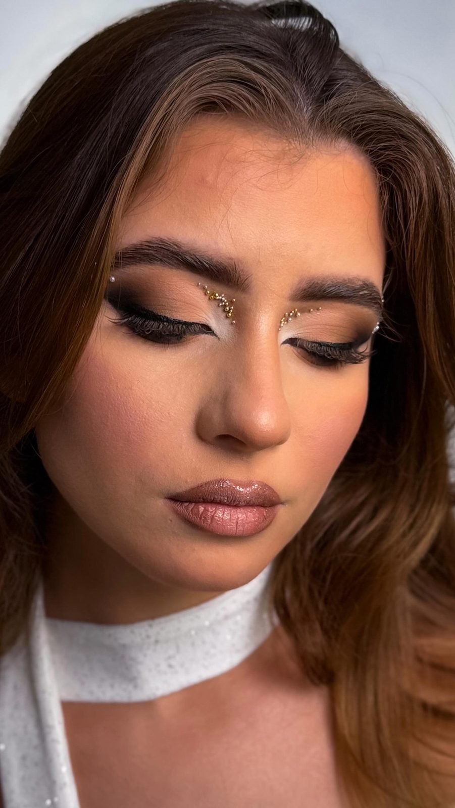 Warme bruine glam met goudglitter in de binnenste ooghoek en een witte choker