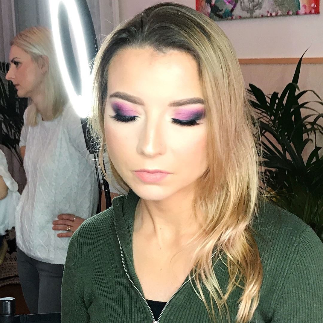 Blond model in een groene trui met paarse en roze oogmake-up, in de studio