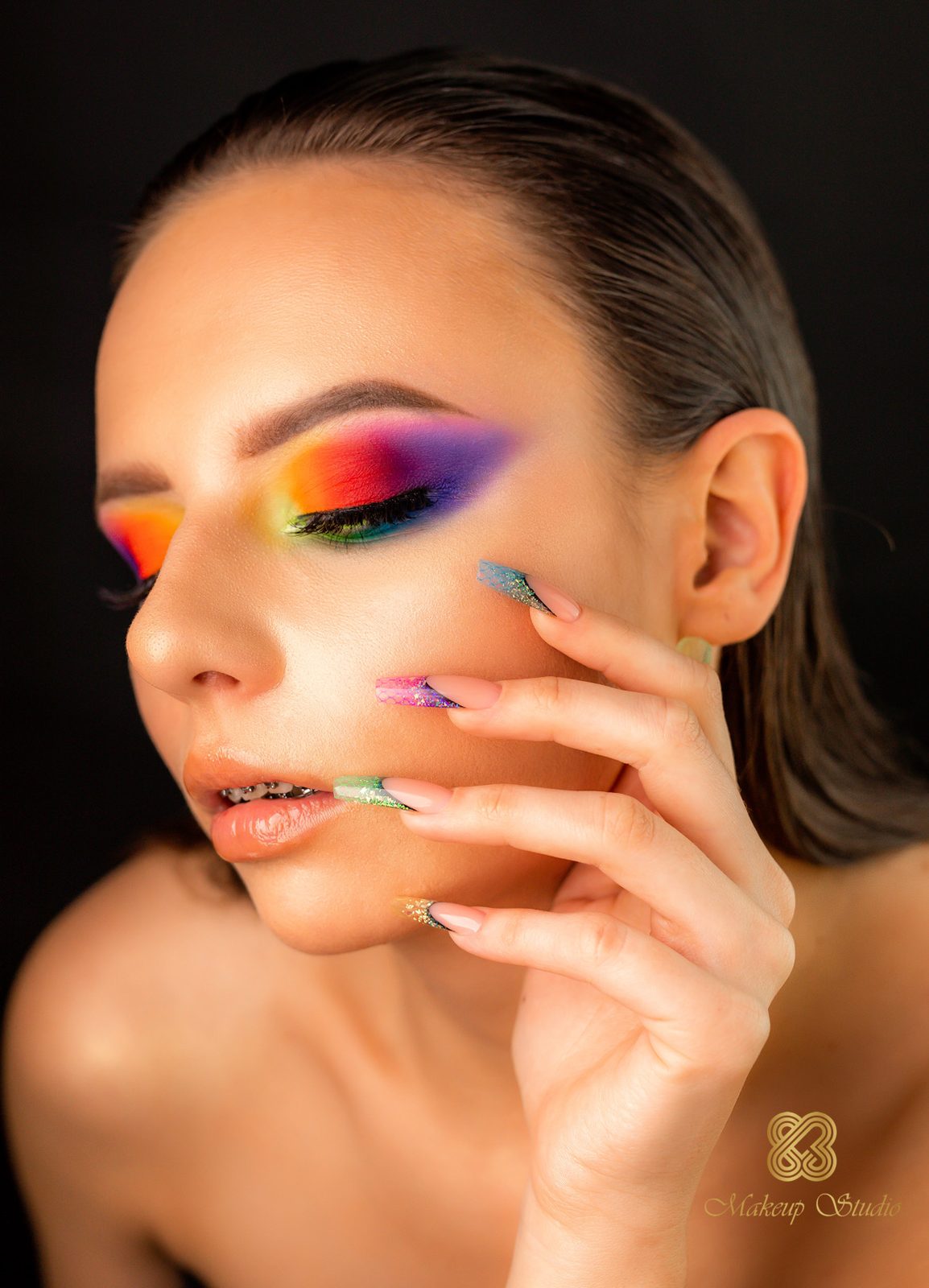 Regenboog-oogmake-up in oranje, rood en paars, lange nagels tegen de wang, donkere achtergrond
